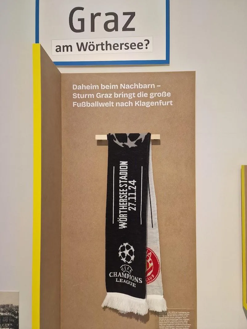 Ausgestellter Fanschal mit der Aufschrift Wörthersee Stadion 27.11.24 und dem Champions-League-Logo